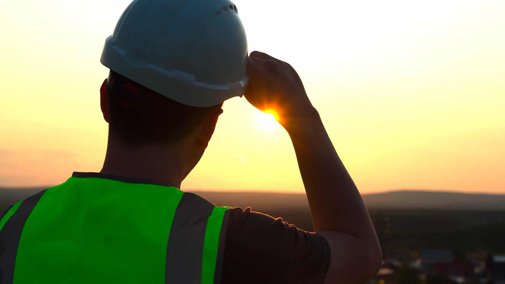 Veiligheidshelm en reflecterend vest bij zonsondergang, bescherming en veiligheid op de werkplek.