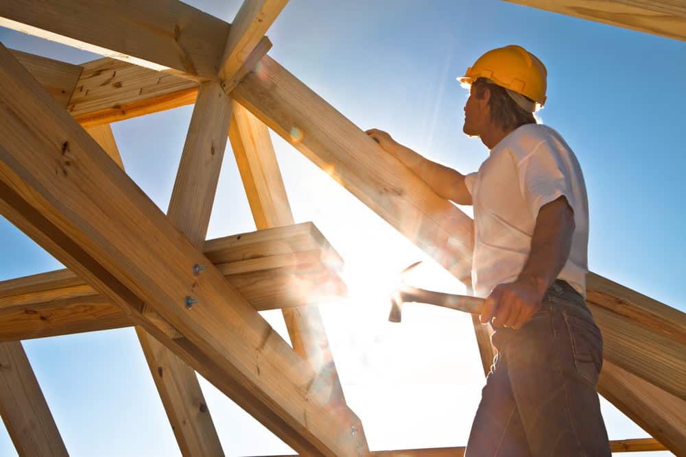 Metaal- en houtconstructie bouwplaats met timmerman en gereedschap bij daglicht, focus op stevig vakmanschap en veiligheid, voor beveiligde bouwprojecten en houtconstructies.